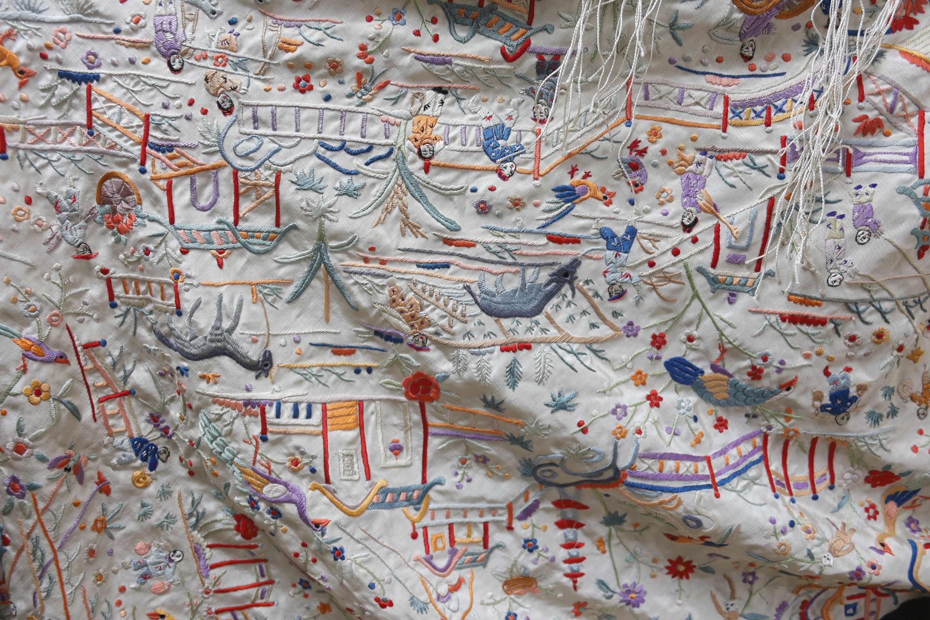 A Chinese cream silk shawl with fine multi coloured all over embroidery depicting figurative scenes and animals